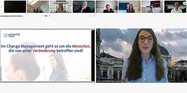 In einer Videokonferenz sind am oberen Bildrand mehrere Personen abgebildet. Links unten ist eine große Präsentation, rechts unten eine Frau mit langen Haaren und Brille groß im Bild