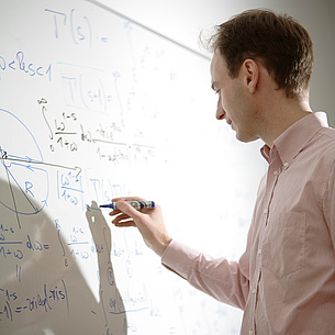 Man performing a calculation on a board. Photo source: Bergmann - TU Graz