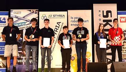 Seven people stand on a stage.