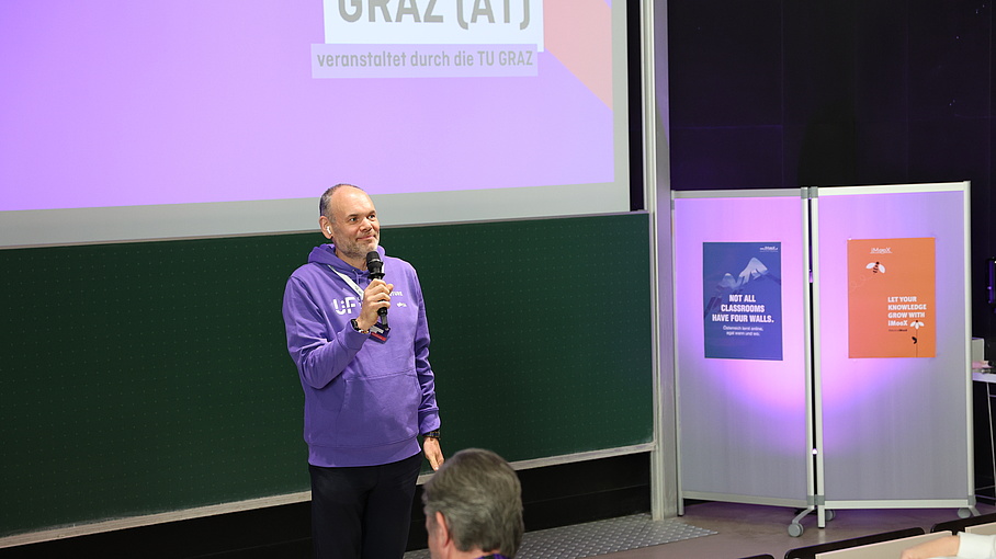 [Translate to Englisch:] Person standing in a lecture hall and giving a speech