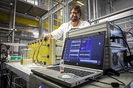A man stands behind a computer and an experimental setup.