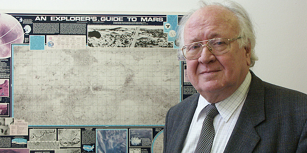 Willibald Rielder posiert  vor einem Plakat mit Weltraumbezug