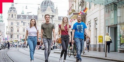 Four young people walk through an inner city street.