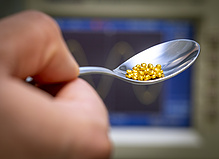 Detail view of gold coloured metal beads on a teaspoon.