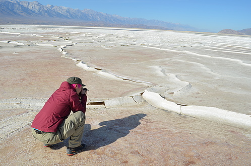 Woman squats on the ground and looks at raised structures on the ground.