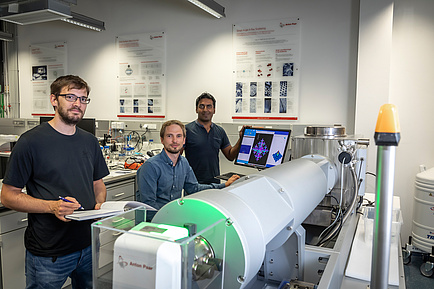 3 men in front of an X-ray measuring machine