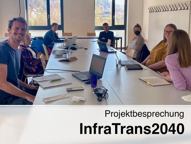 Team des Projektes InfraTrans2040 sitzt um einen Tisch und diskutiert.