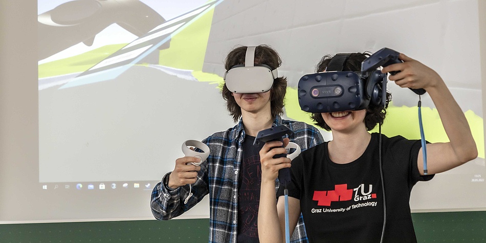 Zwei jung Frauen mit Virtual Reality Brille und Simulation von nicht klar erkennbaren Gegenständen auf einer Wiese im Hintergrund.