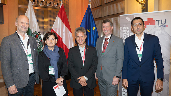 Five people, four men and one woman, smile into the camera