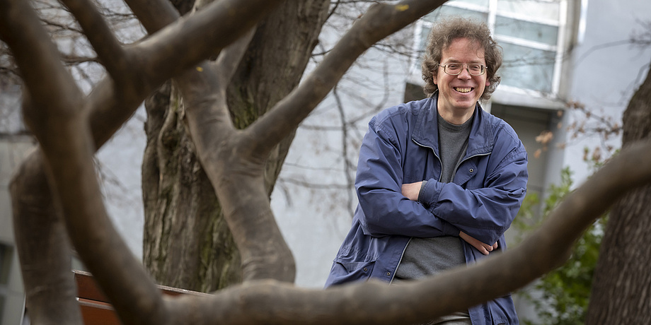 A man is standing next to a tree.