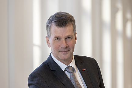 A man in a suit smiles into the camera