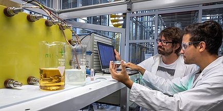 Zwei Forscher der TU Graz vor einem Versuchsaufbau mit Redox Flow Elektrolyte