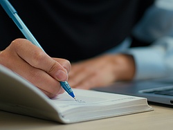 Eine Person hält einen Stift in der Hand.
