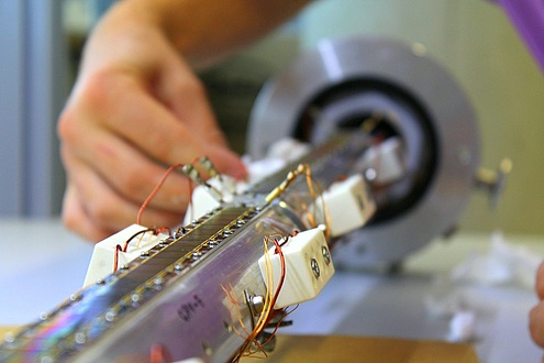 A row of narrow silicon solar cells lies in a tube that is open at the top.