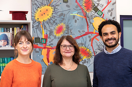 Two female researchers and one male researcher in front of a painting with flowers