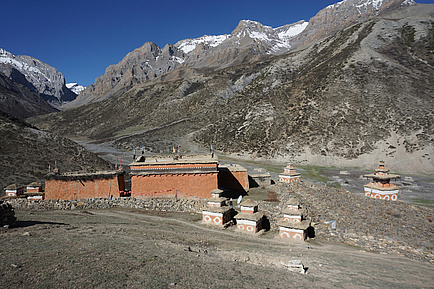 In front of a mountain range stand several brick buildings.