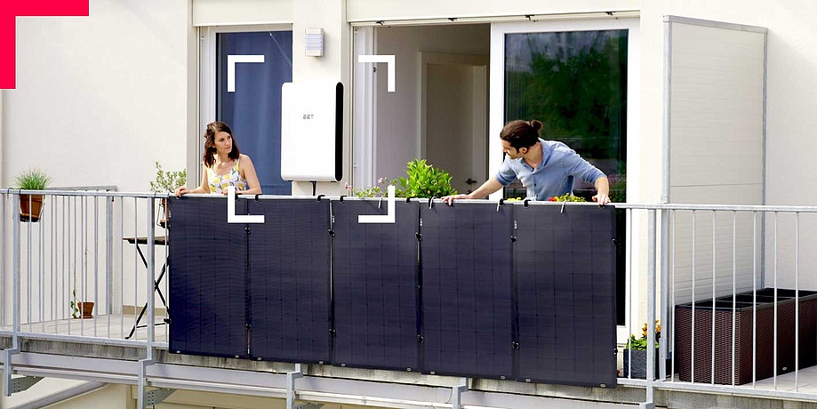 Mann und Frau beugen sich über ein Balkongeländer mit Solarpanelen.