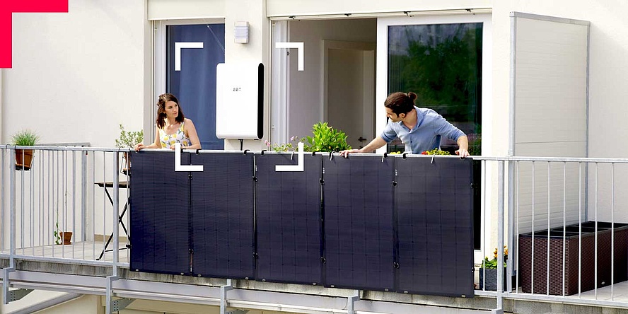 Man and woman bending over a balcony railing with solar panels.