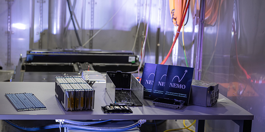 An open battery pack for an electric car is sitting on a table. Next to it are small cards bearing the word ‘Nemo’.