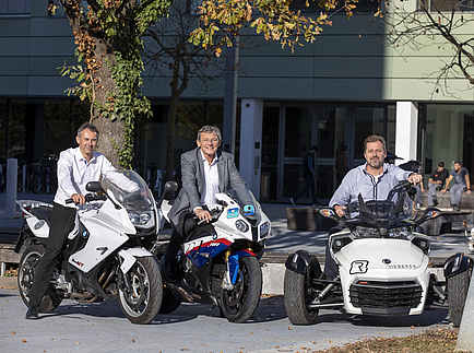 Three men sit on Personal Mobility vehicles - two motorcycles and a Powersport device 