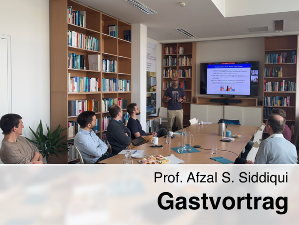 Prof. Afzal S. Siddiqui hält einen Gastvortrag vor einer kleinen Gruppe in einem Bibliotheksraum, während auf dem Bildschirm eine Präsentation mit dem Titel „Transformation of the Huge Power Sector“ gezeigt wird.