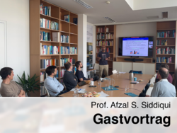 Prof. Afzal S. Siddiqui hält einen Gastvortrag vor einer kleinen Gruppe in einem Bibliotheksraum, während auf dem Bildschirm eine Präsentation mit dem Titel „Transformation of the Huge Power Sector“ gezeigt wird.