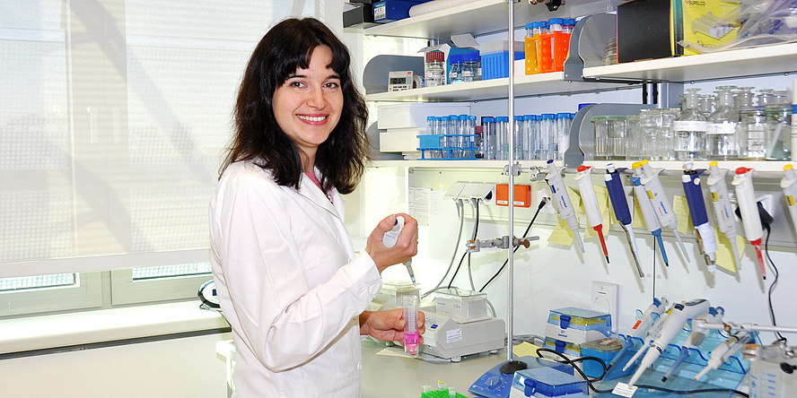 Kateryna Lypetska steht im Labor, in den Händen hält sie eine Pipette und eine Eprouvette.