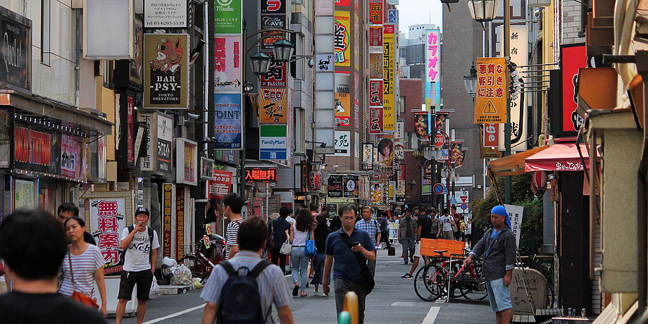 A lively street. Lots of commercials. People are walking around.