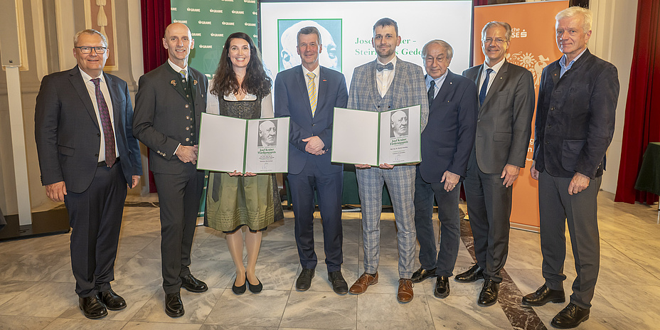 Eine Gruppe von acht Personen, zwei davon halten Urkunden.