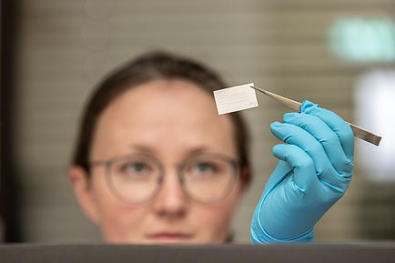 Researcher holds tattoo sensor with tweezers in the air