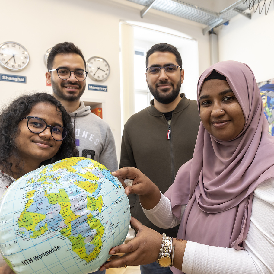 Four international students are holding a globe.