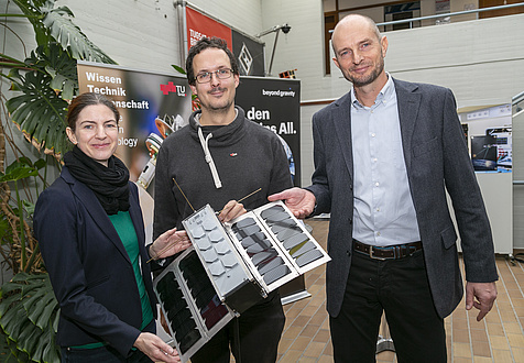 A woman and two men with a satellite model.