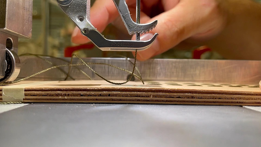 The needle of a sewing machine sews pieces of wood together using nylon thread.