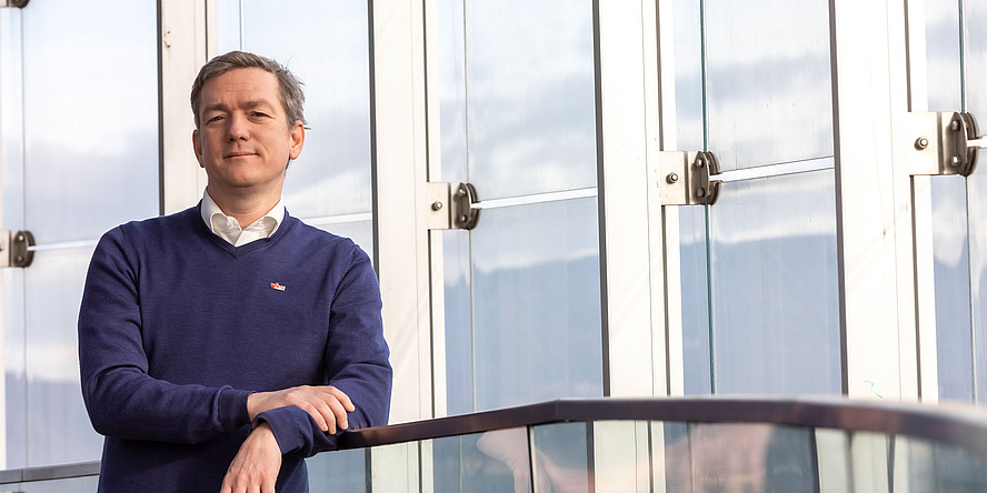 Researcher stands in front of a glass parapet 