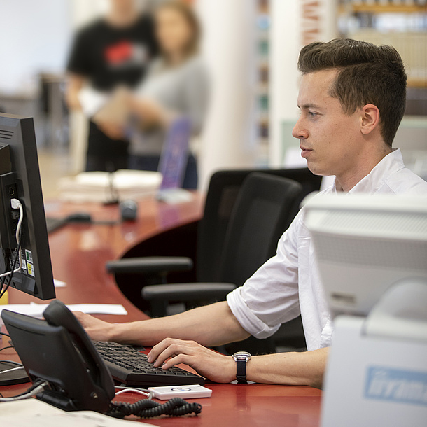 Ein Mann sitzt an einem Tisch vor einem Computer.