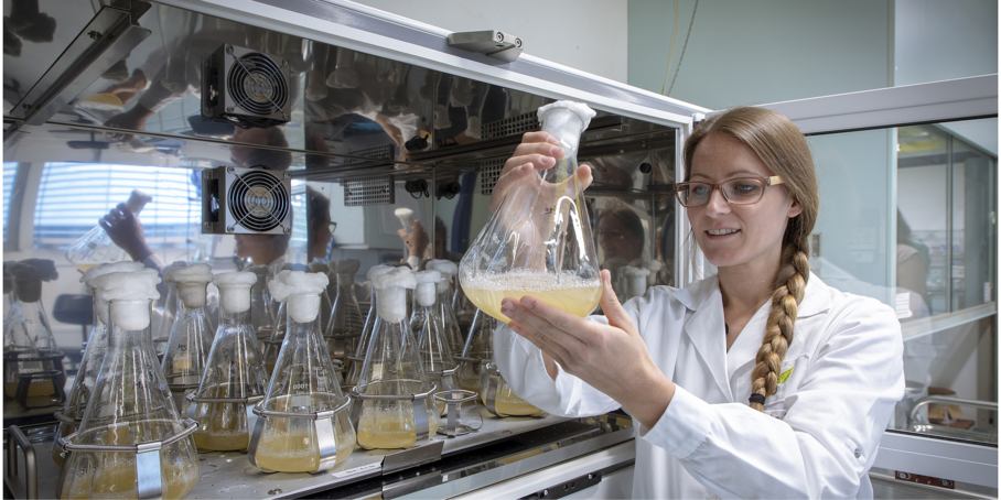 Young researcher holding vessel with liquid.