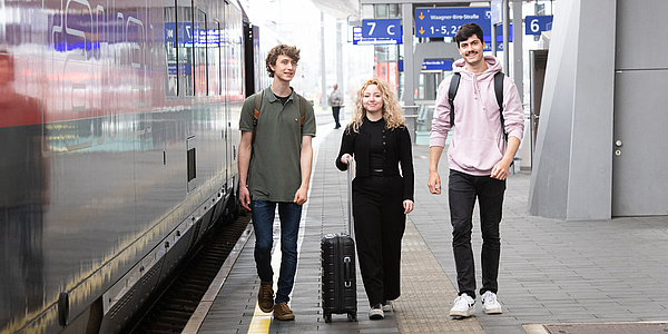 Junge Menschen am Bahnhof mit Koffer
