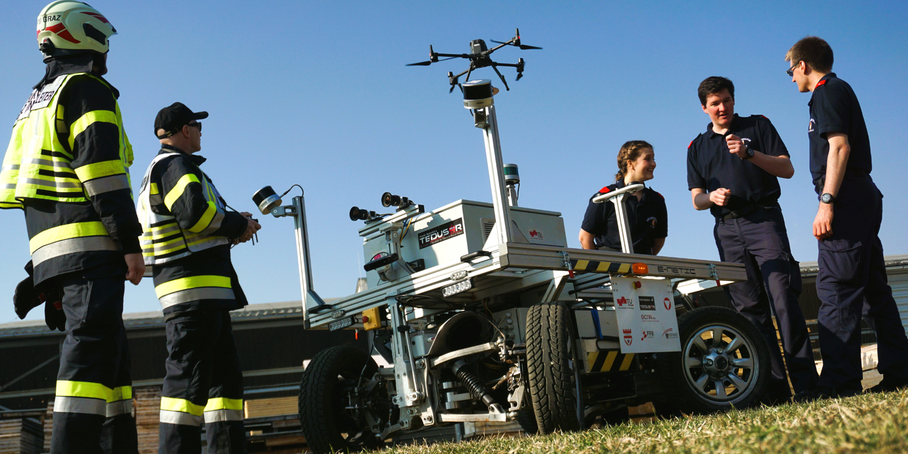 Firefighters stand by a robot and a drone.