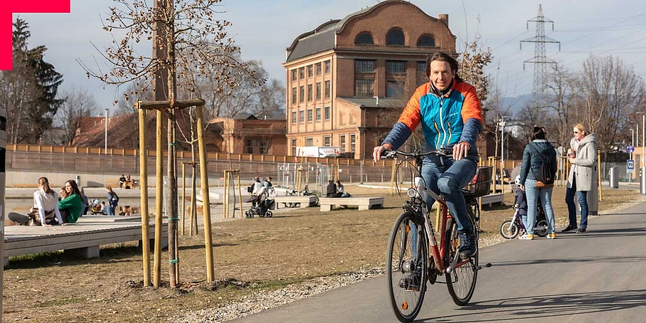 Man on bicycle riding through busy park