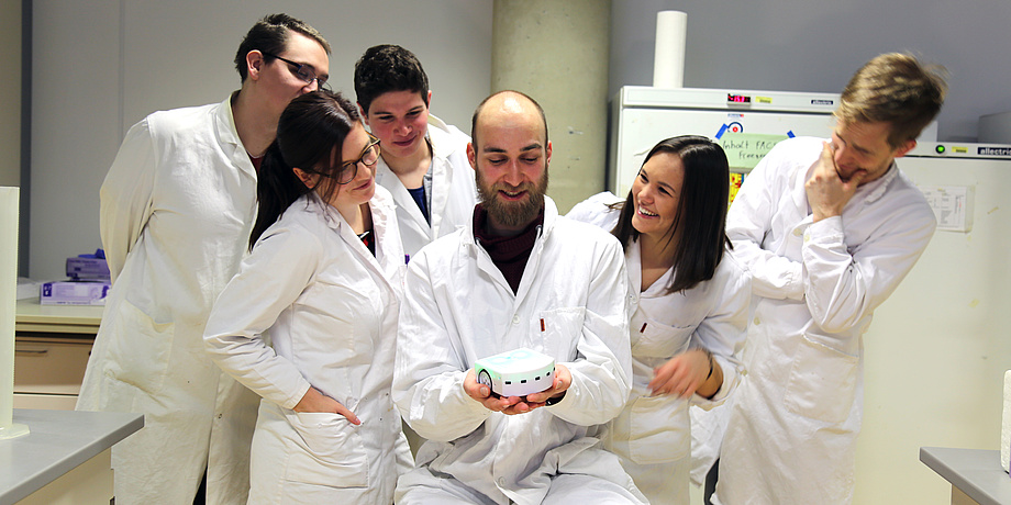 Six members of the current iGEM team in white coats in the laboratory.