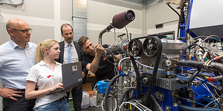 The leading team of AVL-TU Graz Transmission Center next to a gearbox