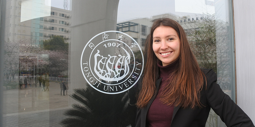 Clara Fischer vor ihrem Büro im Chinesich-Deutschen Haus der Tongji Universität, deren Logo sichtbar ist