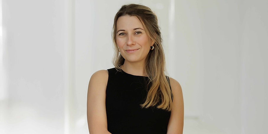 A woman with brunette hair and black shirt looks smiling into the camera.