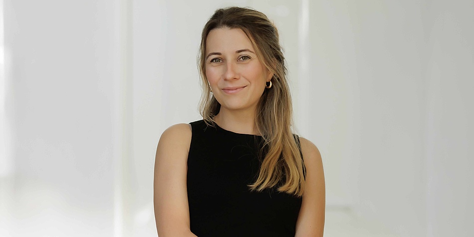 A woman with brunette hair and black shirt looks smiling into the camera.