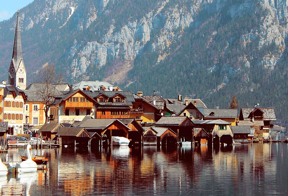 Picturesque houses with a church densely packed on the lake in front of mountains.
