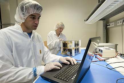 Wissenschaftliche Mitarbeiter/in beim Bau von TUGSAT-1 im Reinraum an der TU Graz.