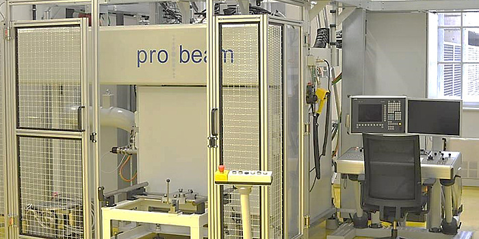 A large white machine built inside a white cage. The doors are open. There is a control panel on the right sight next to the machine.