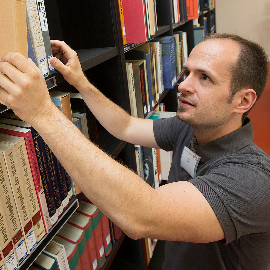 Ein Mann nimmt ein Buch aus einem Bücherregal