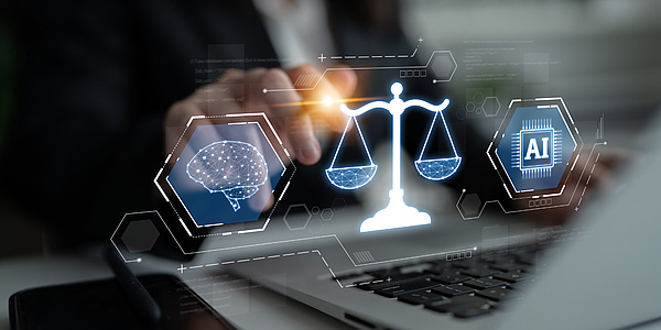 Eine Person tippt auf der Tatsatur eines Laptops, über dem ein Hologramm ischwebt, das eine Waage, ein Gehirn und einen Mikrochip darstellt.