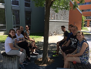 Members of the institute and summer trainees sitting outside on benches.